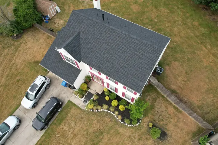 Completed dark roof on a red-shuttered two-story home