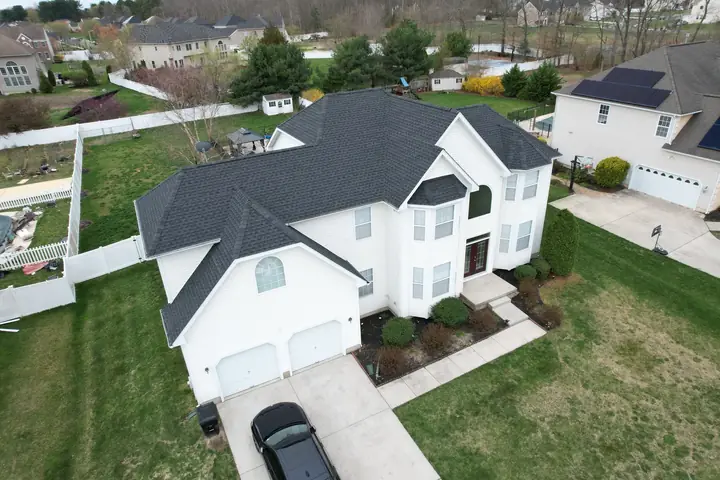 Black roof replacement on a large white home
