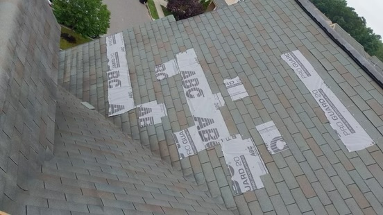 White temporary roof protection installed over exposed shingle areas